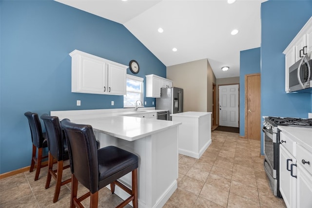 kitchen featuring stainless steel appliances, a kitchen island, white cabinets, vaulted ceiling, and light countertops