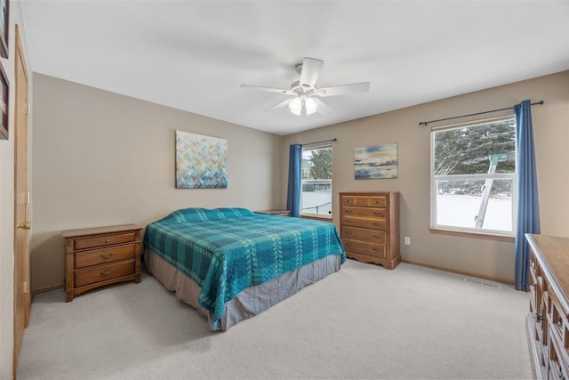 bedroom featuring baseboards, multiple windows, a ceiling fan, and light colored carpet