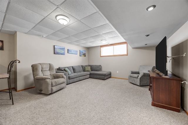 carpeted living room featuring a paneled ceiling and baseboards