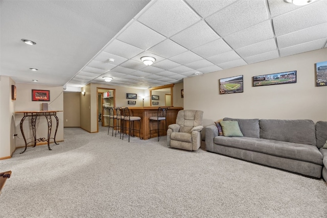 carpeted living room with a dry bar, baseboards, and a paneled ceiling