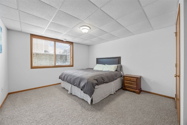 carpeted bedroom with a paneled ceiling and baseboards