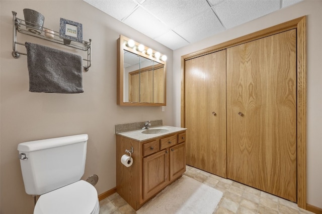 bathroom featuring toilet, baseboards, a paneled ceiling, and vanity