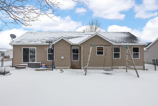 snow covered rear of property with central air condition unit and fence