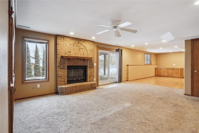 unfurnished living room featuring carpet floors, a healthy amount of sunlight, a brick fireplace, and recessed lighting