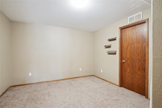 carpeted spare room featuring a textured ceiling, visible vents, and baseboards