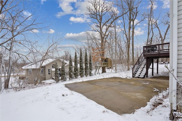 snowy yard with a garage, stairs, and a deck