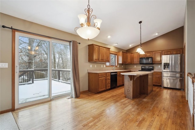 kitchen featuring a center island, light countertops, brown cabinetry, light wood-type flooring, and black appliances