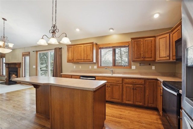 kitchen with electric stove, light countertops, a healthy amount of sunlight, a kitchen island, and a sink