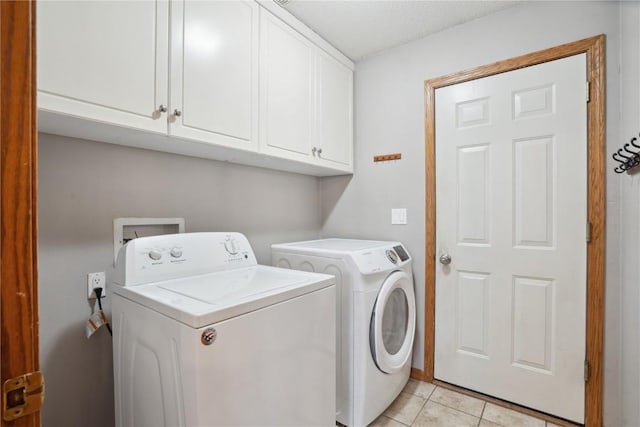 laundry room with washing machine and dryer, cabinet space, and light tile patterned floors