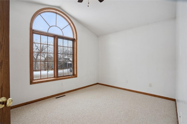 carpeted spare room featuring lofted ceiling, baseboards, visible vents, and ceiling fan