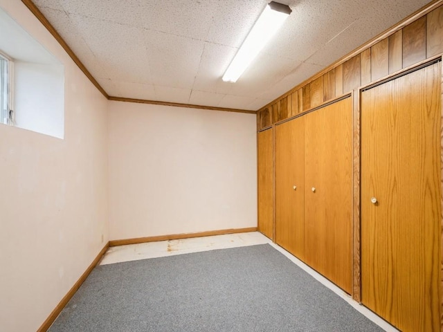 finished below grade area with crown molding, carpet flooring, and baseboards