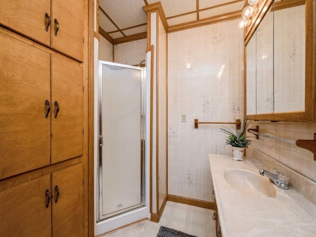 full bath featuring a stall shower, vanity, and tile walls