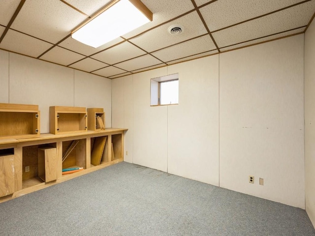 below grade area with carpet floors, a drop ceiling, and visible vents