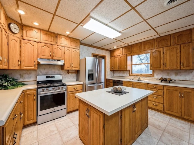 kitchen featuring a kitchen island, stainless steel appliances, light countertops, under cabinet range hood, and a sink