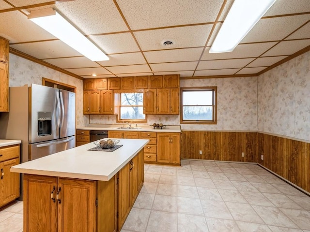 kitchen featuring a sink, wainscoting, stainless steel fridge, and wallpapered walls