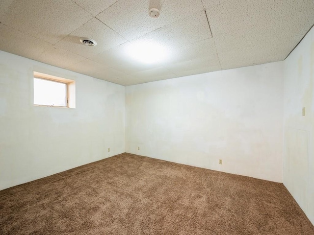 below grade area featuring a paneled ceiling, visible vents, and carpet flooring