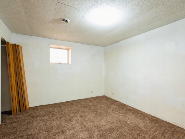 unfurnished room featuring a drop ceiling, carpet, and visible vents