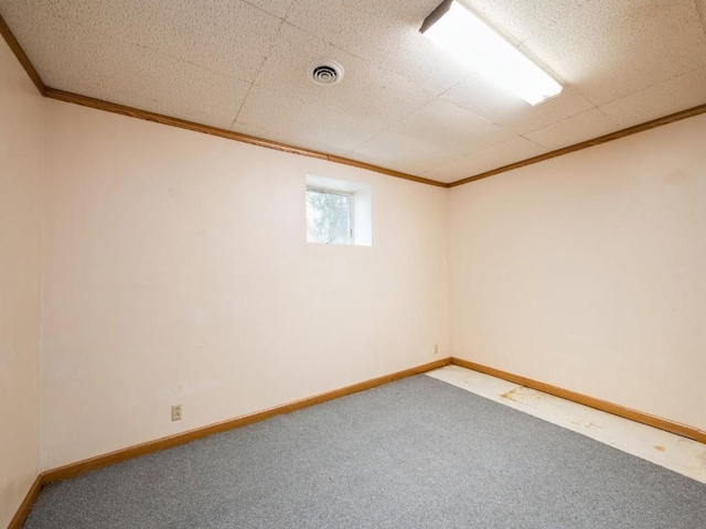 carpeted empty room with visible vents, crown molding, and baseboards