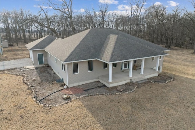 exterior space featuring a porch, a shingled roof, and driveway