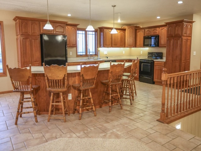 kitchen with a center island, brown cabinets, recessed lighting, light countertops, and black appliances