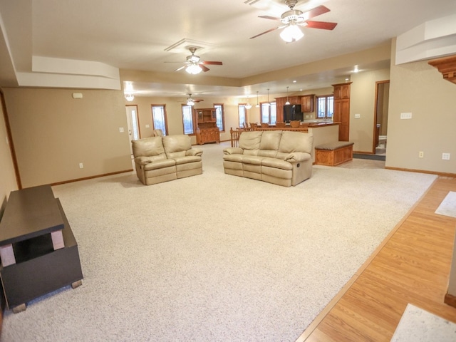 living area featuring light wood finished floors, a ceiling fan, and baseboards