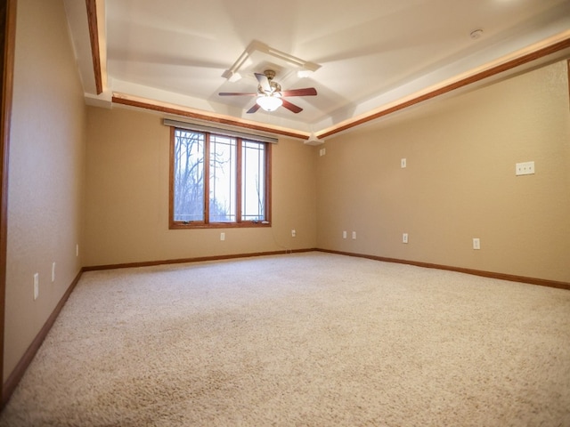 empty room with light carpet, baseboards, a tray ceiling, and ceiling fan