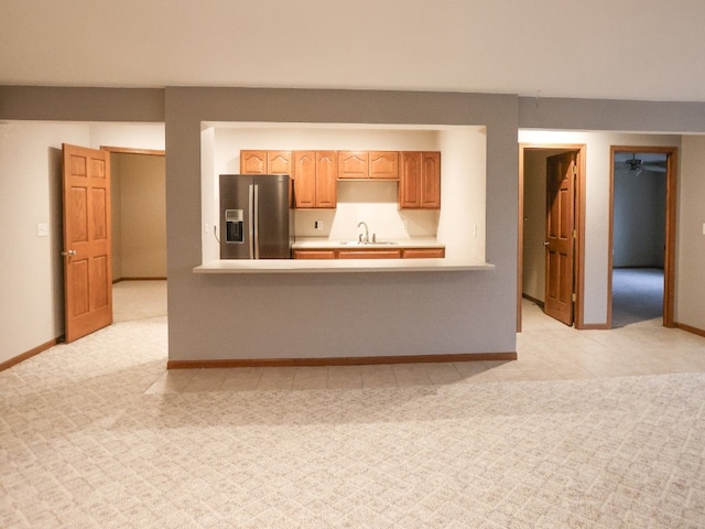 kitchen with light colored carpet, a sink, baseboards, light countertops, and stainless steel fridge