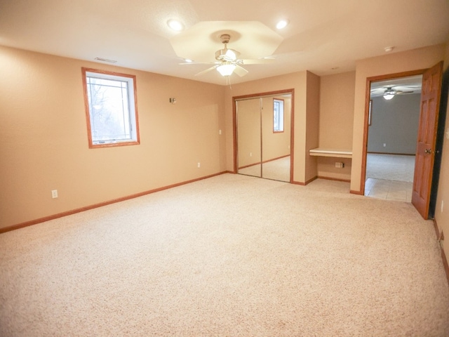 unfurnished bedroom featuring ceiling fan, baseboards, a closet, and light colored carpet