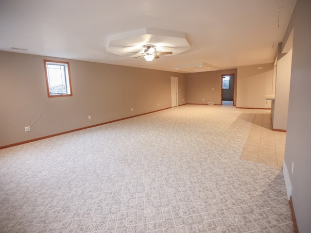 carpeted spare room featuring tile patterned flooring, baseboards, and a ceiling fan