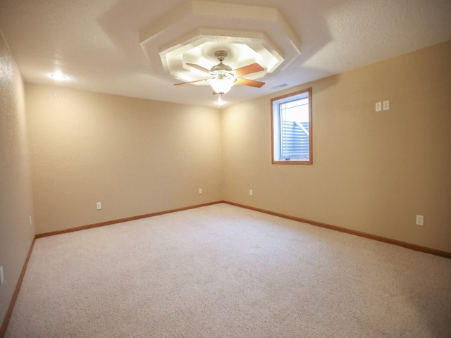 spare room featuring light carpet, ceiling fan, visible vents, and baseboards