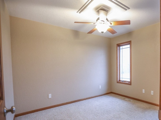 carpeted empty room with visible vents, ceiling fan, and baseboards