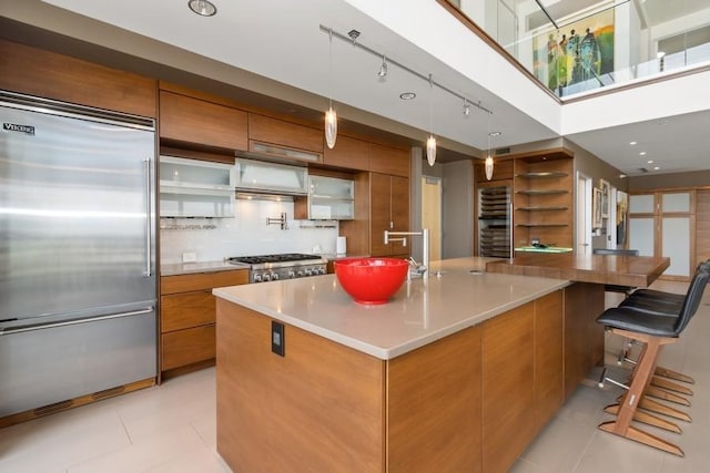 kitchen featuring stainless steel appliances, light tile patterned floors, brown cabinetry, and modern cabinets