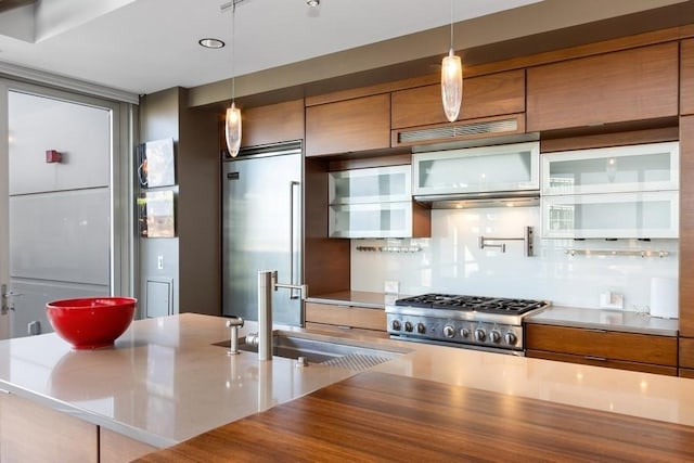 kitchen with a sink, stove, built in fridge, and brown cabinets