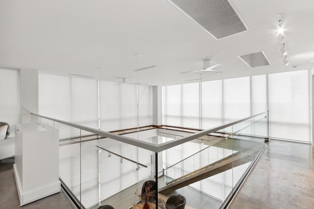 hall with concrete flooring, rail lighting, and visible vents