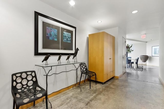 corridor with baseboards, recessed lighting, and finished concrete floors