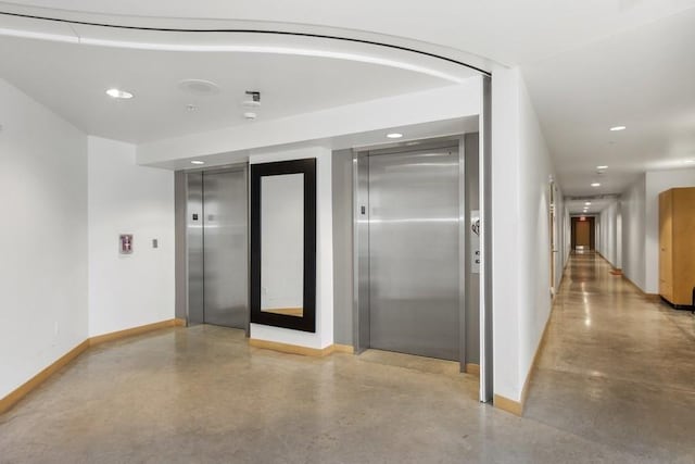 corridor featuring finished concrete floors, recessed lighting, elevator, and baseboards