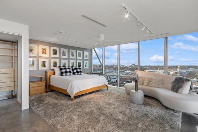 bedroom featuring rail lighting, floor to ceiling windows, concrete floors, and multiple windows