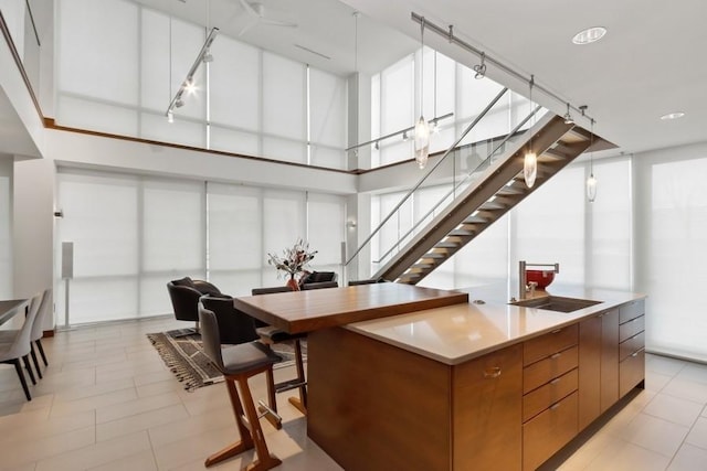 bar featuring a towering ceiling, light tile patterned floors, stairs, and a sink