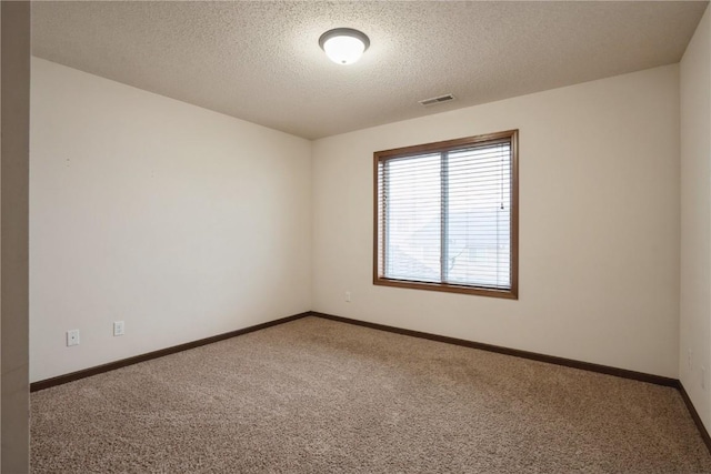 unfurnished room with carpet flooring, visible vents, baseboards, and a textured ceiling