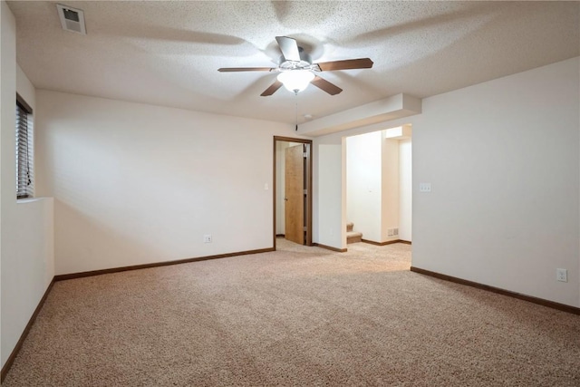 empty room featuring a textured ceiling, light carpet, visible vents, and baseboards