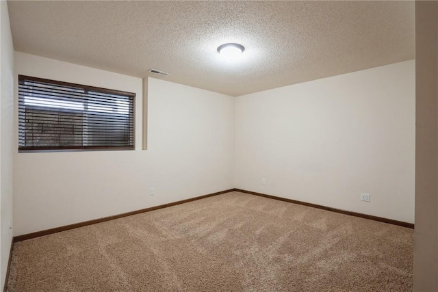 empty room featuring carpet floors, baseboards, visible vents, and a textured ceiling