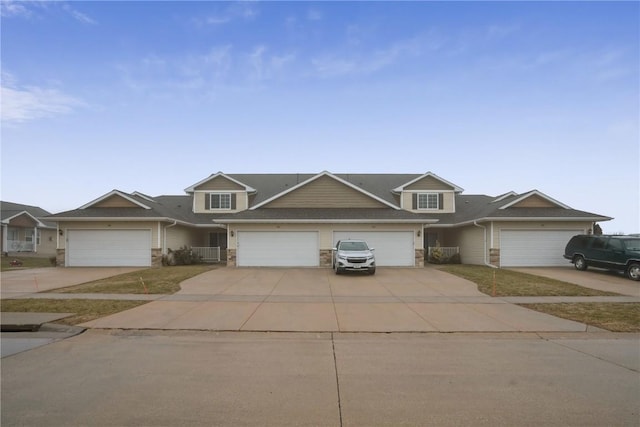 view of front of house featuring an attached garage, stone siding, and concrete driveway