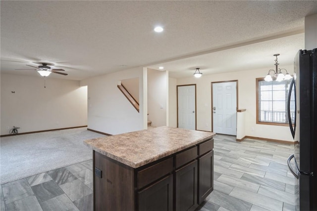 kitchen with a textured ceiling, light countertops, ceiling fan with notable chandelier, and freestanding refrigerator