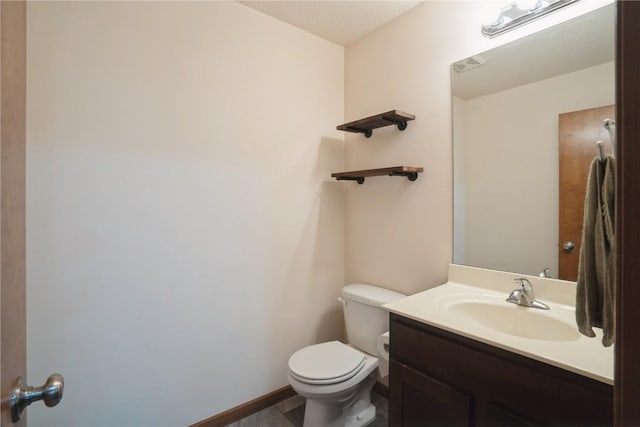 half bathroom with vanity, toilet, and baseboards