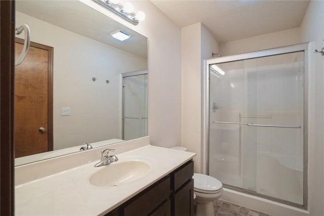 bathroom featuring vanity, a shower stall, and toilet