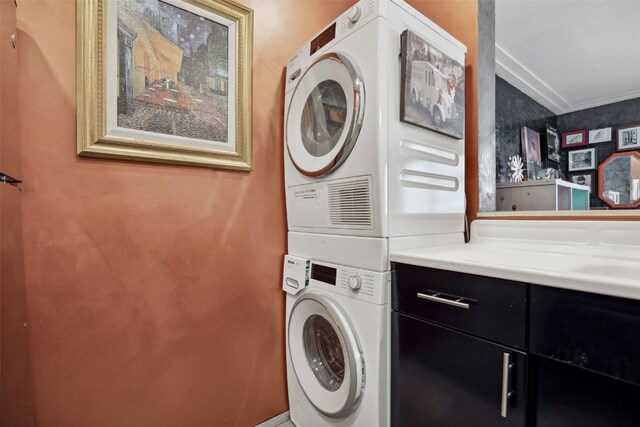 400 1st St SE Unit 203, Cedar Rapids, IA 52401 - washroom featuring estacked washer and dryer, crown molding, and cabinet space