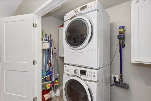 laundry room with laundry area, stacked washer / dryer, and wood finished floors