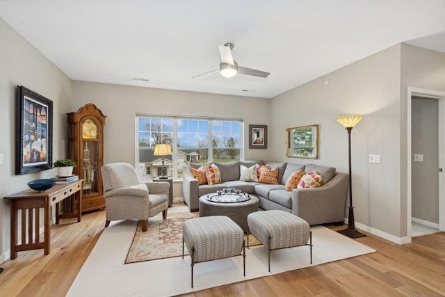 living area with light wood-style flooring, baseboards, and a ceiling fan