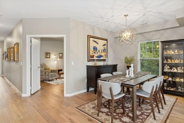 dining area with a chandelier, visible vents, light wood-style flooring, and baseboards