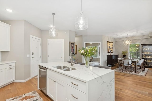 kitchen with dishwasher, a center island with sink, light wood-style floors, and a sink